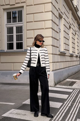 a lady in a black mock neck sweater, a striped cardigan and a pair of black pants